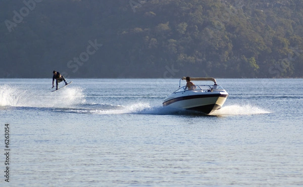 Obraz waterkier wyskakuje w powietrze za szybką motorówką