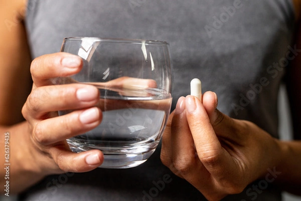 Obraz Taking tablets with water, dietary supplements in capsules, supplementing with vitamins and minerals