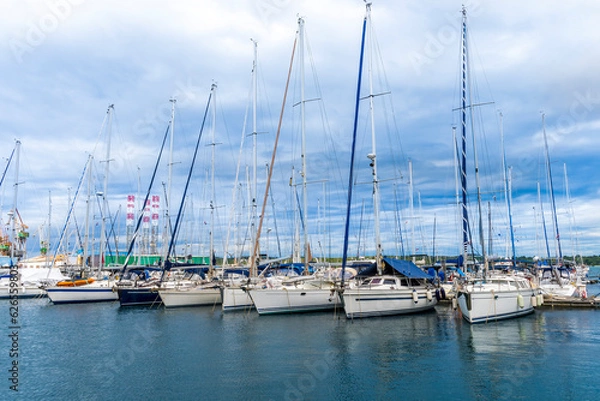 Obraz boats and yachts on pier in marine city port with masts and bulidings and blue sky on background , water cityscape of urban port