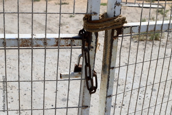 Fototapeta An old padlock hangs on the gate.