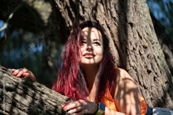 Obraz Portrait of a girl on a tree in a city park in summer