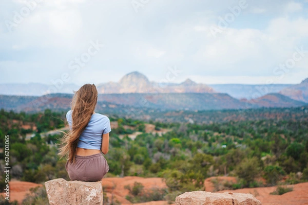 Fototapeta Girl enjoys the view of the Sedona landscape from the top of the Bell Rock hiking trail, famous for its many energy vortexes and red rocks.