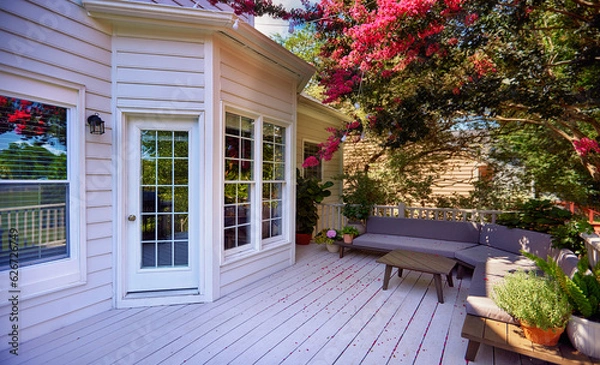 Fototapeta beautiful wooden terrace under the blooming crape myrtle. lounge zone in the summer garden