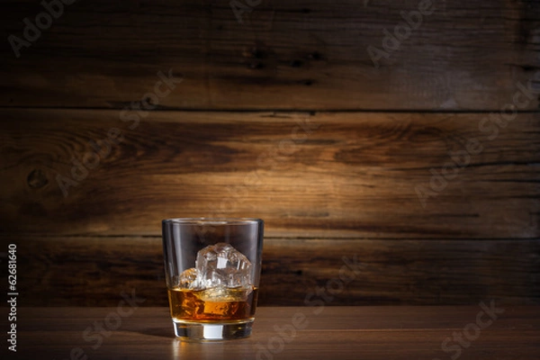 Obraz kieliszek whisky z lodem na tle drewnianych