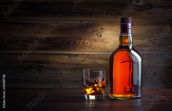 Obraz butelka i kieliszek whisky z lodem na tle drewnianych
