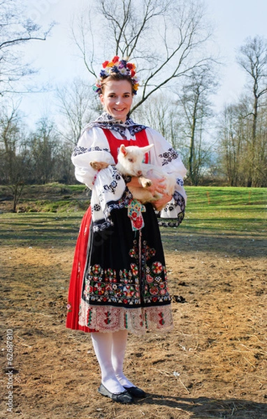 Obraz The smiling girl in folk costume with little lamb