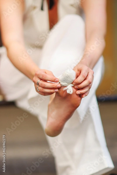 Fototapeta girl bandaging her toe outside
