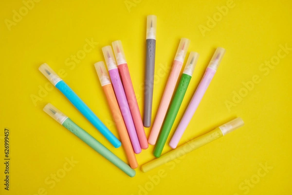 Fototapeta Many colorful markers on a colored background, flat lay. School stationery. The concept of study, office and drawing