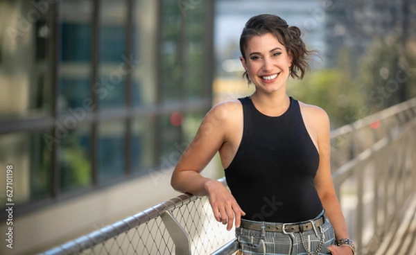 Fototapeta Modern lifestyle portrait of a friendly woman with a charming smile, smiling in downtown urban background with copy space