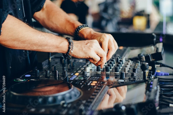 Fototapeta Hands of a DJ working with a mixing console close-up.