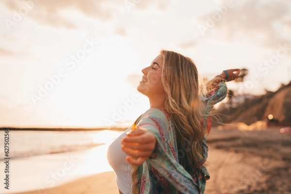Fototapeta Portrait of one young woman at the beach with openened arms enjoying free time and freedom outdoors. Having fun relaxing and living happy moments..
