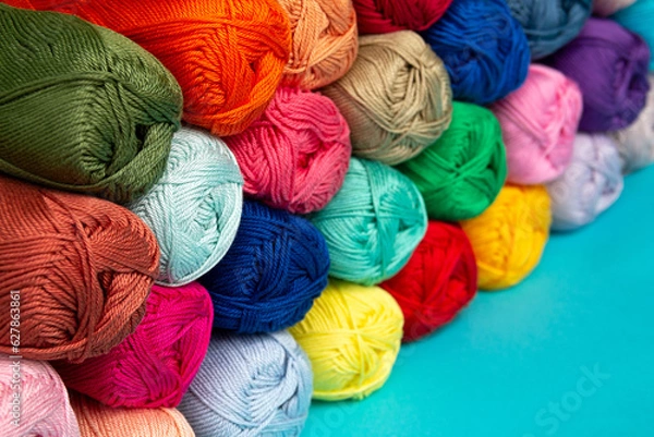 Fototapeta Multi-colored skeins of cotton yarn stacked on top of each other in perspective. Materials for knitting. Textile industry. Arranged balls of yarn. Small depth of field.