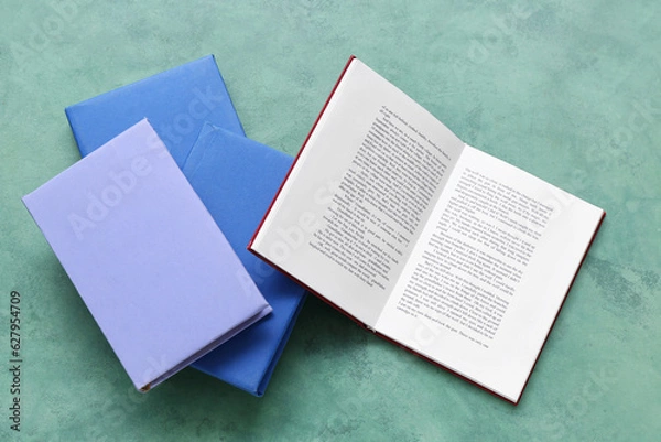 Fototapeta Open and closed books on green table