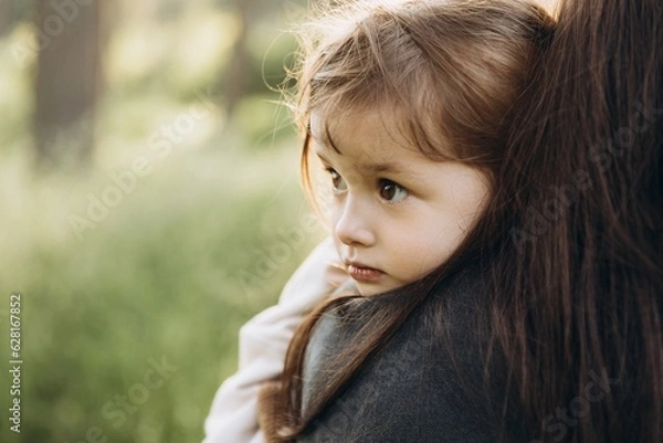 Obraz a little girl walks in a coniferous forest among tall grass before sunset