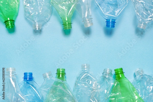 Fototapeta Flat crushed bottle crumpled plastic garbage PET recycling background trash. Flat plastic bottle recycling design blue paper. Row empty bottle PET plastic recycling concept. Reuse. Used. Waste sorting