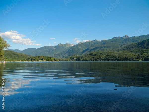 Fototapeta Mountain reflection on wavy water surface of lake Bohinj on a sunny summer day.