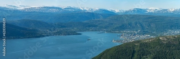 Fototapeta Panorama of ship leaving Mo i Rana through Ranfjorden, Helgeland, Norway. High megapixel image of big boat in fjord between high norwegian mountains in summer. View from Hauknestinden, snow on fjell.