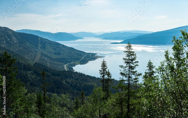 Fototapeta Panorama over Ranfjorden going west from Hauknestinden, 800 m altitude. Peak of Hauknes, Mo i Rana. Mountains dramatically going down into the fjord water below. Clear skies during Norwegian summer.	