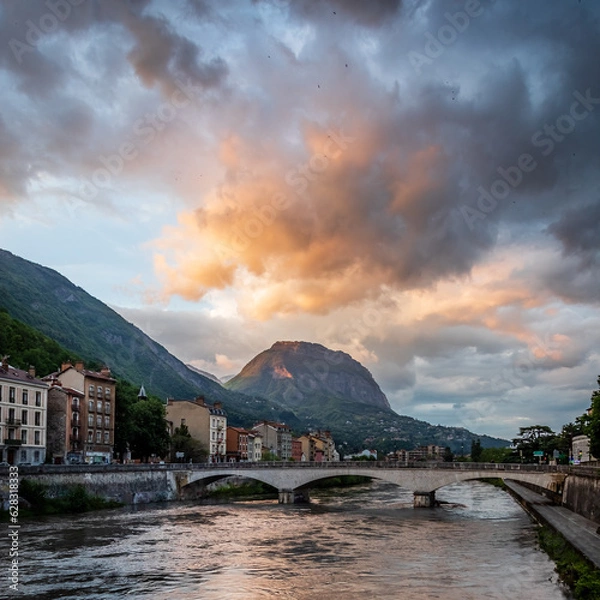 Fototapeta Dawn landscape featuring mountains, bridge, city skyline, and reflective river