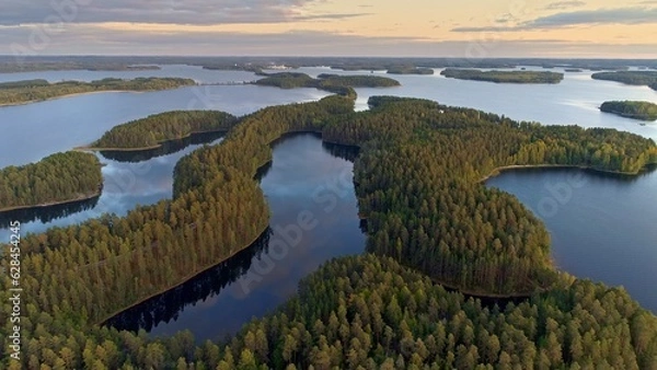 Obraz Flying over lakeland in Finland. Aerial shot of many green islands at sunset - classical Finnish landscape. Finnish Lake land in sunset lights. Green islands and lake with clouds reflection. 4K, UHD