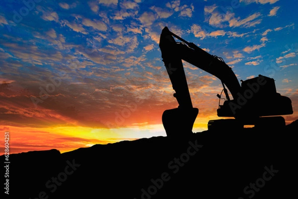 Fototapeta Crawler excavators silhouette are digging the soil in the construction site on the sunset background