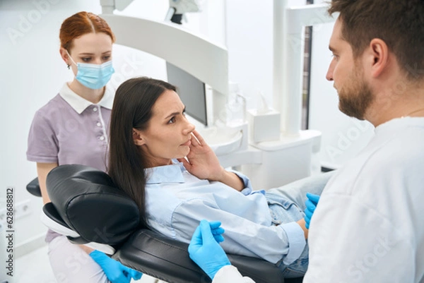 Fototapeta Woman patient complaining to dentist on dull and constant toothache
