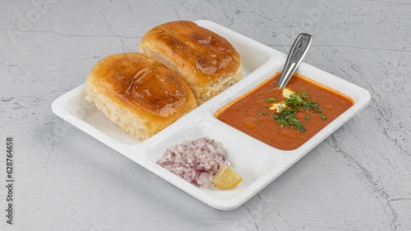 Fototapeta Indian Mumbai Street style Pav Bhaji, garnished with peas, raw onions, coriander, and Butter. Spicy thick curry made of out mixed vegetables served with pav over textured background with in white plat
