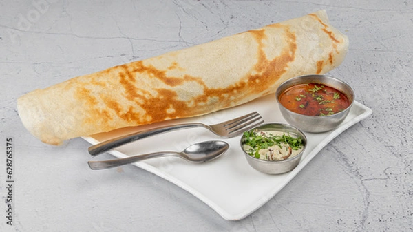 Fototapeta Plain Dosa – A South Indian pancake in white plate with chutney and sambhar (curry) garnished and styled, on textured background