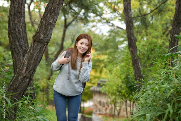 Fototapeta a young female college student traveling through the woods with a backpack