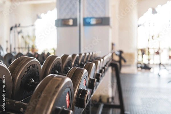Fototapeta heavy workout gym with multiple equipment randomly working out in a gym with a strong big muscle and big body in a city gym, modern equipment in a dark theme in an indoor gym with white people
