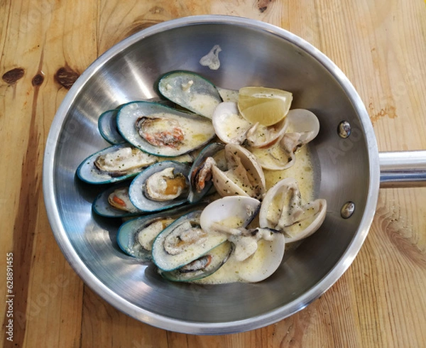 Fototapeta Mussels Clams Kiwi in cheese sauce in cooking pan on wooden background