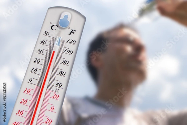 Fototapeta Man pouring water on his head in extreme heat, Thermometer in summer day shows or indicate high temperature