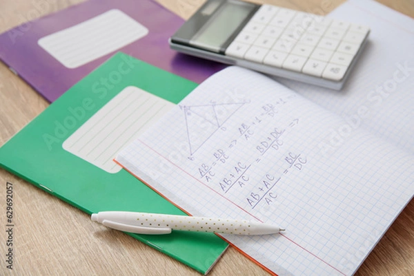 Obraz Open copybook with formulas, calculator and pen on wooden table