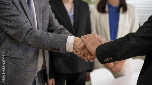 Fototapeta closeup with cropped shot two businesspeople having handshake with both hands after negotiation. agreement and partnership concept