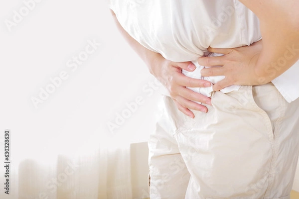 Fototapeta お腹が痛そうな若い女性