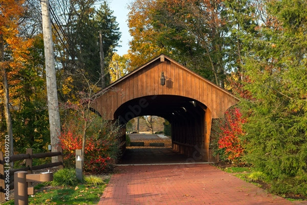 Fototapeta View through an old covered bridge, for pedestrians only, that stands at the edge of a popular park near Cleveland, Ohio