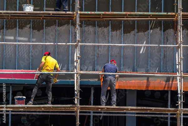 Fototapeta Workers on scaffolding at a construction site