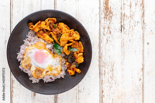 Obraz stir fried chicken with red curry paste, bergamot leaves, pepper with rice and egg in ceramic plate, top view, flat lay, copy space for text, Thai food, Gai Pad Prik Gaeng, Spicy Red Thai Stir Fry