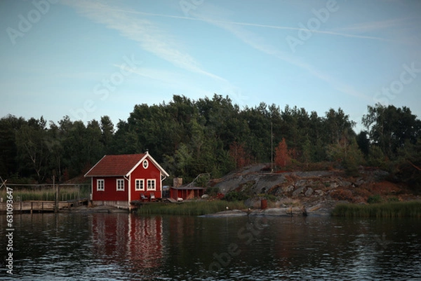 Obraz red wooden hut in a forest in Sweden by a lake. Peace in nature and ideal place for vacation