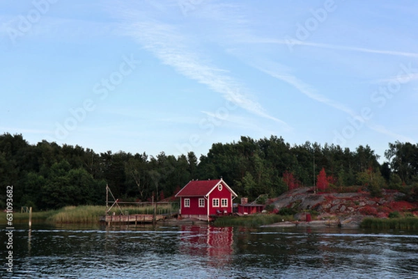 Obraz red wooden hut in a forest in Sweden by a lake. Peace in nature and ideal place for vacation