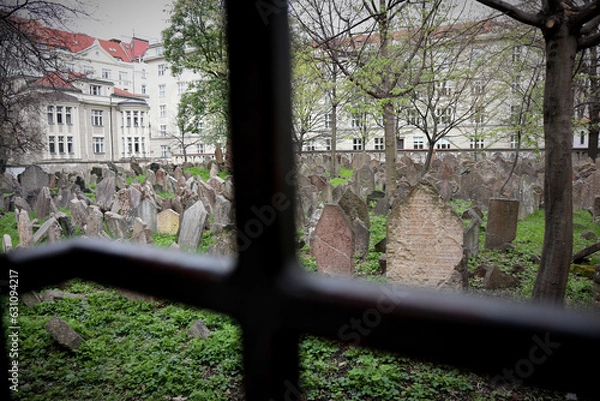 Obraz Very old and weathered Jewish gravestones in a walled-in cemetery in Prague photographed through a small iron-barred peephole