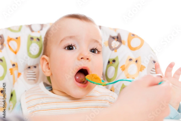 Fototapeta Happy mother feeds hungry baby from a spoon