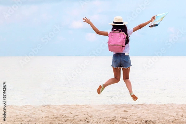 Fototapeta Summer Party. Traveler and tourism woman travel in summer on the beach and white sand. Asian is jumping  with pink backpack and map. On travel in vacation concept