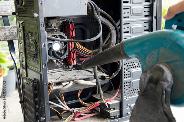 Fototapeta Photograph of a technician blowing dust from a computer