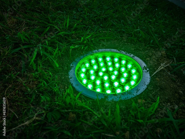 Fototapeta Turned on green light. Street illumination lamp in the ground. Lantern in the ground. Palm lighting.