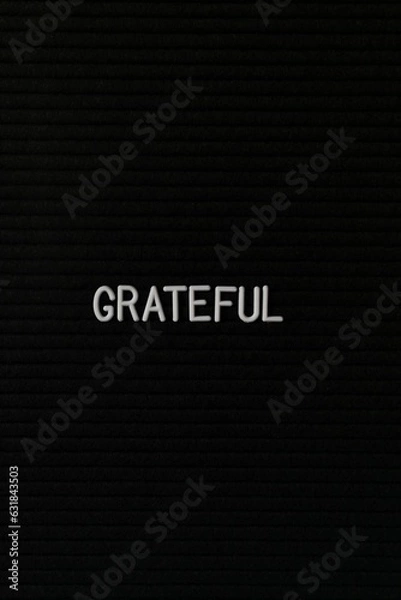 Fototapeta Vertical black spongy board with a text "grateful" for background