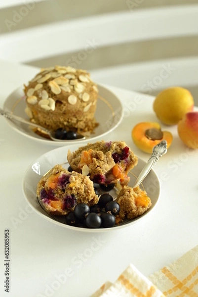 Fototapeta Muffins with apricots and black currants sprinkled with almond flakes, vertical