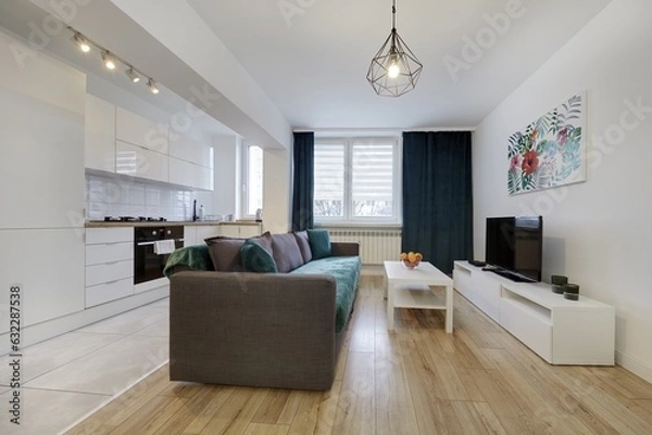 Obraz Nowoczesny apartament z zielona sofą, telewizorem i otwartą kuchnią