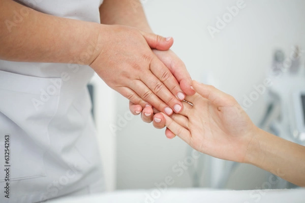 Fototapeta Close up massage of a woman's hands in the interior of a beauty salon on a white background