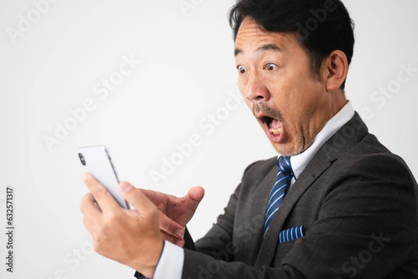 Fototapeta スマートフォンを持って驚いているミドル男性　ビジネスイメージ